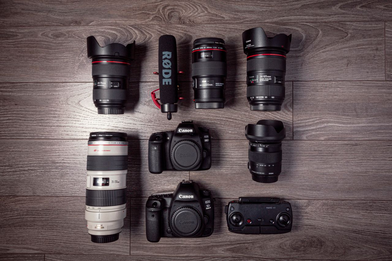 Flat lay of professional photography equipment including cameras, lenses, and microphone.